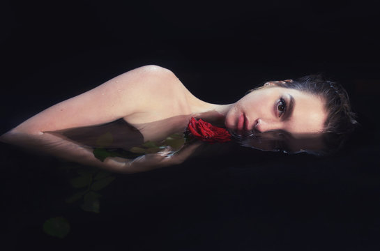 girl with bright makeup and flowers in her hair in the pool on a black background