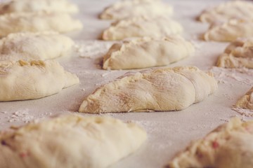 Fototapeta na wymiar Raw homemade pies lie on the table with flour