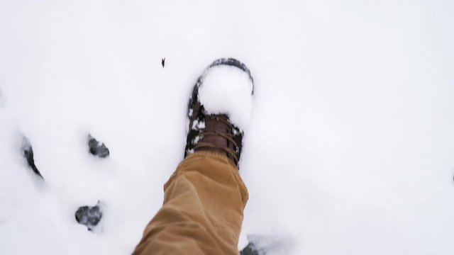 Mans legs and boots walking through deep snow looking straight down in slow motion