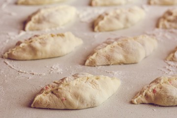 Raw homemade pies lie on the table with flour