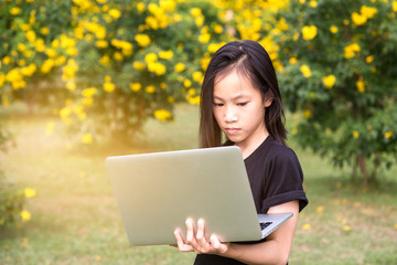 Asian girl is using a laptop in the garden