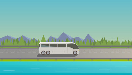Touristic white bus driving on freeway. Nature background, mountains, trees, lake.