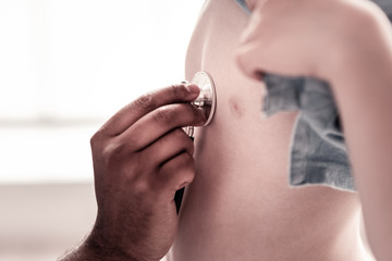 Fototapeta premium Health is important. Scaled up look on a little boy visiting doctor during a checkup and checking his heart at a clinic.