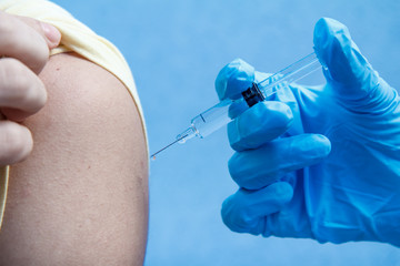 Hand of doctor holding syringe for vaccination to upper arm of patient