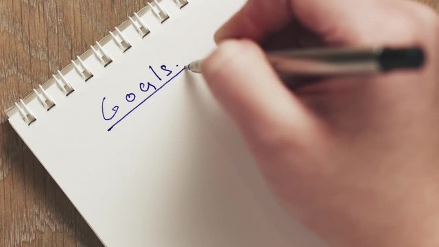 female teen writes goals on blank notepad