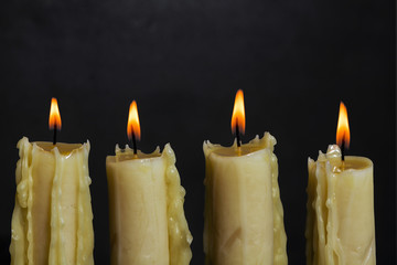 Four candles are in the row on a black background. 