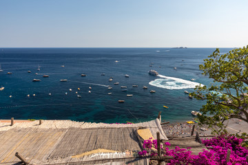 Fototapeta premium Positano framed by pink bougainvillea and boats in the background. Italy