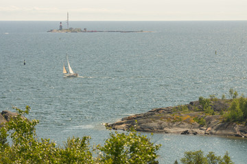 A boat sailing in the calm Baltic sea on a summer day next to the Suomenlinna island in Finland, Europe