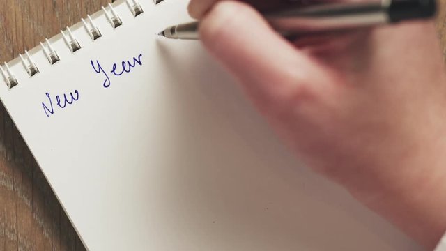 female teen writes new year goals on blank notepad