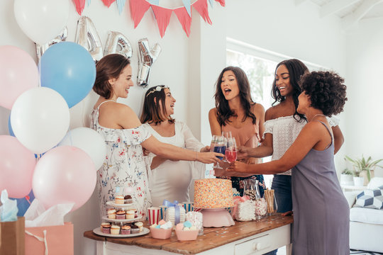 Women toasting with juices at baby shower party