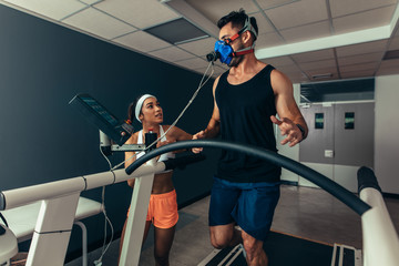 Athlete running on treadmill with female trainer