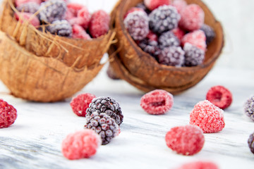 Frozen black and red raspberries in coconut bowl.