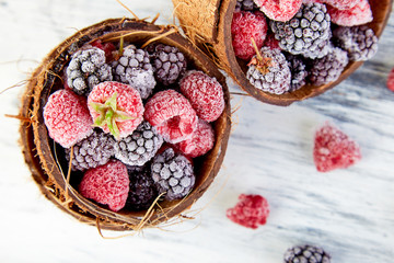 Frozen black and red raspberries in coconut bowl.