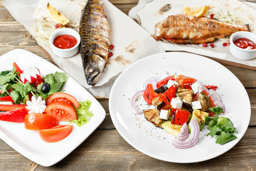 grilled mackerel and sea bass. Salad of fresh vegetables. Serving on a wooden Board on a rustic table. Barbecue restaurant menu, a series of photos of different meats anf fish