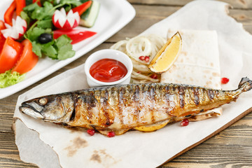 grilled mackerel and a salad of fresh vegetables. Serving on a wooden Board on a rustic table. Barbecue restaurant menu, a series of photos of different meats anf fish