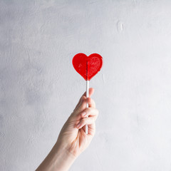 Candy heart in the women hand on concrete background. Minimal concept about love and relationship. Love concept. Romantic Style, Creative for colorful greeting card with copy space.