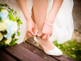 the bride puts on her shoe, next to her is the bridal bouquet