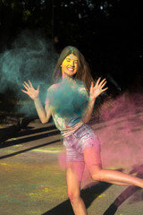 Positive brunette model celebrating Holi festival in the park