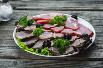nicely sliced meat on plate, on wooden background in rustic style