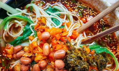 Spicy noodle soup with vegetables, herbs, peanuts and coriander, popular in Yunnan Province, shallow depth of field, China.