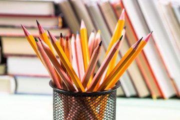 Set of pencils and pile of various books on wooden background. With copy space for your text