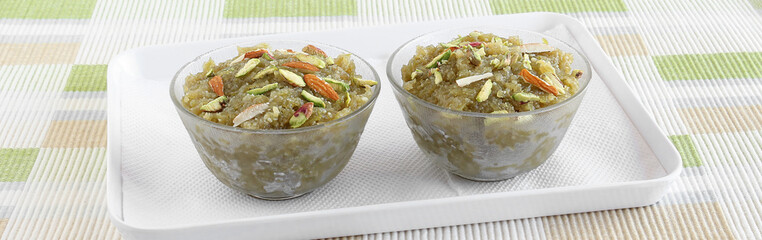 Lauki halwa, also known as doodhi, ghiya, or bottle gourd halwa, is a traditional and popular Indian sweet dish, in two glass bowls on a tray.