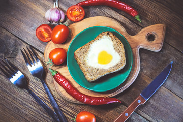 fried bread. fried eggs in a heart-shaped symbol. vegetables. on a wooden board