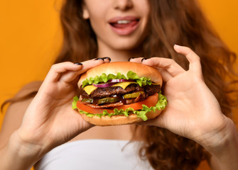 Woman eat burger sandwich with hungry mouth on yellow background
