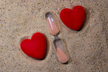 Fototapeta premium hourglass against a background of sand with symbols of the heart