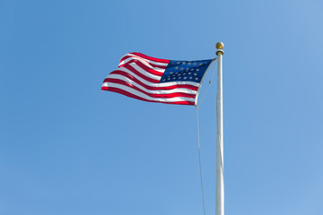 American flag on the blue sky background, turned to the left