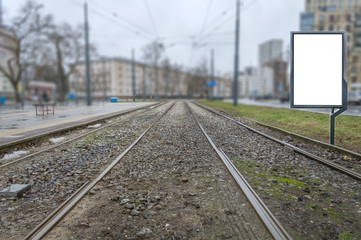 Empty advertising billboard on tram railway in the city street on raining day