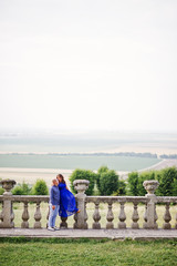 Lovely couple in love against old castle. Girl in blue dress.