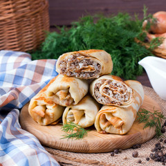 Crepes stuffed with minced meat and rice on a cutting board on a wooden table