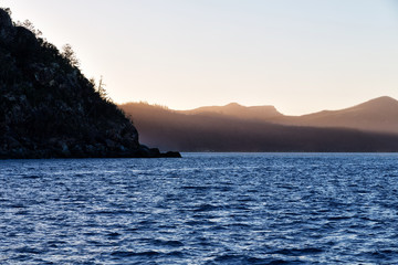 the sunrise in the ocean near the mountain