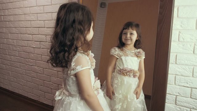 Little girl in a beautiful dress in front of a mirror.
