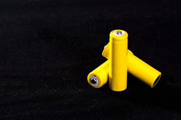Three yellow batteries close-up on a dark black blurred background. Electrics. Battery power. ...