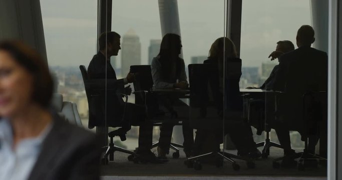 4K Laid back corporate business team laughing & joking in boardroom meeting in city office. Slow motion.