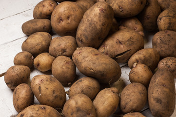 A lot of dirty potatoes on a rustic background.