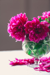 red peonies in glass vase stand on table