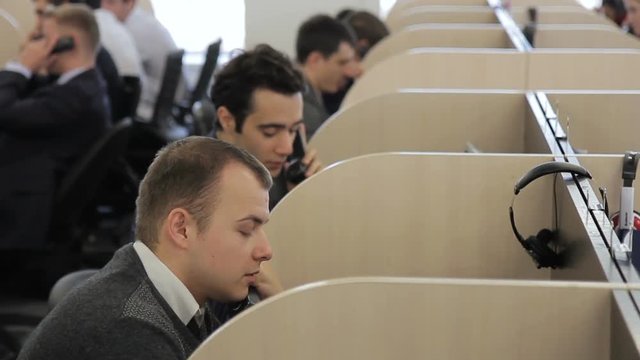 The stuff of the teleshop works in the big open space calling to the clients. The workers sit at the tables, which and talk to the customers using their phones or headphones. The office is devided by