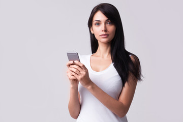 Fototapeta premium young girl holding mobile phone and looking away