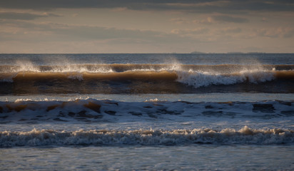 Surf spray blowing off the top of waves at Rhossili bay on the Gower peninsula, Swansea, Wales, UK
