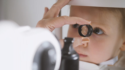 Cute child in ophthalmology clinic - optometrist diagnosis little blonde girl