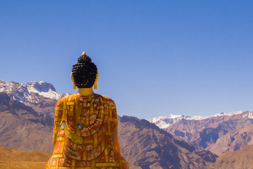 Buddha statue looking at mountains and sky