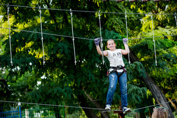 Little girl in an amusement park passes an obstacle course