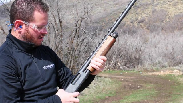 Slow motion man expels shotgun shell from gun