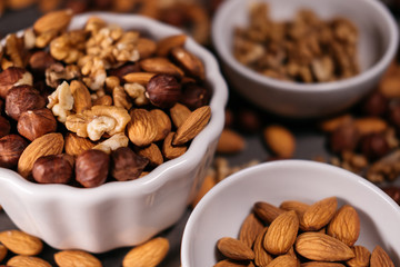 Three white cups filled with nuts, almonds, hazelnuts, walnut and.