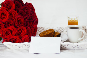 Breakfast in bed, celebrate valentines day, womens day or birthday. White bed, large bouquet of red roses. In the background of a pillow, a bedside table unfocus. copy space, free space.