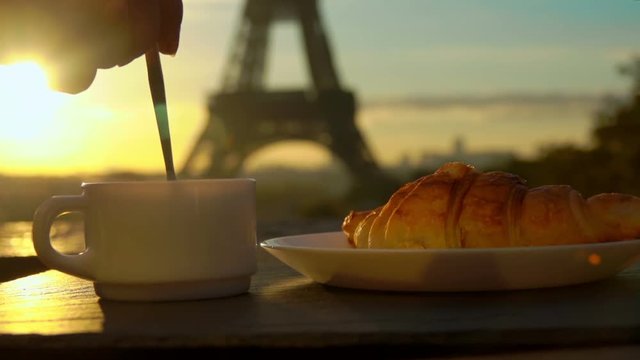 Cup of coffee with a croissant on a sunny morning in the background of the Eiffel Tower