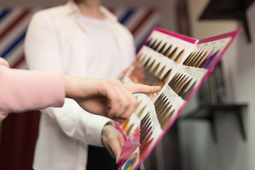 Image of a young client choosing hair color in the hair salon
